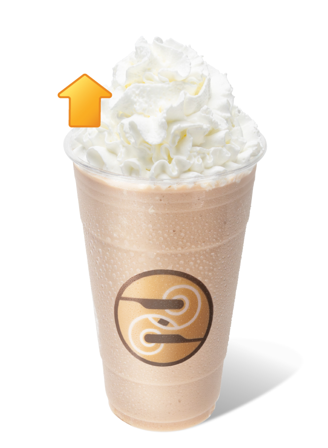 Ziggi's Coffee Frozen Protein Chai Blender in a clear cup with a creamy tan blend topped with whipped cream