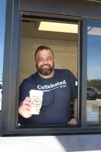 Photo of Hamilton Barnes, owner of Ziggi's Coffee in Huntington, IN, holding a drink out of the drive-thru window