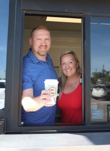 Ziggi's Coffee owners James and LuAnn Barrett from Saco, ME location, holding a drink outside the drive-thru window